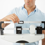 Young man adjusting a medical weight scale.