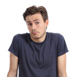 Front portrait of a young man doubting shrugging shoulders isolated on a white background