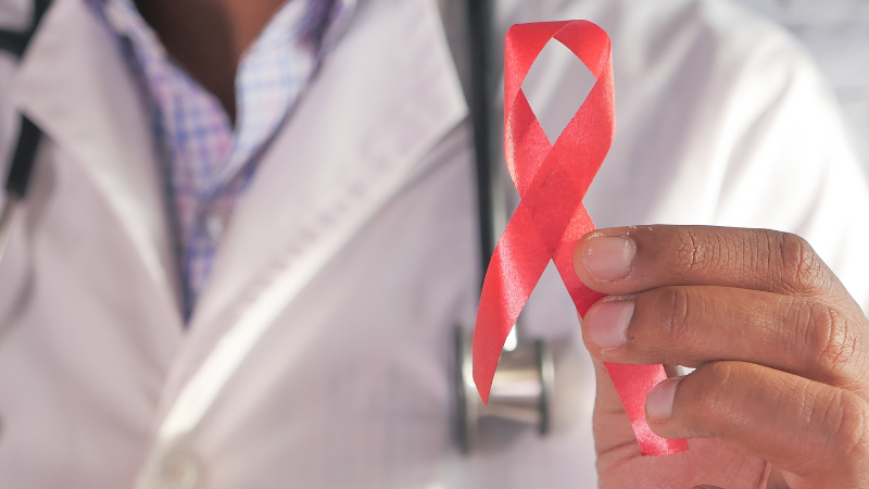 Person holding a red HIV/AIDS awareness ribbon.