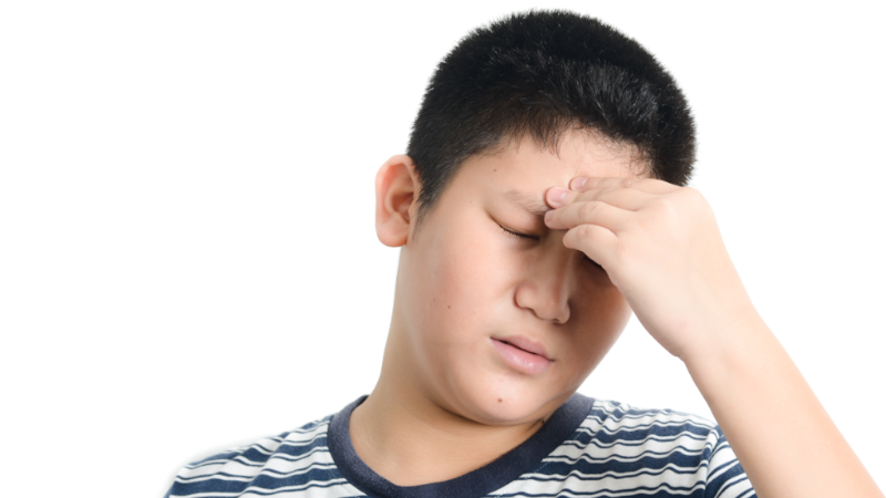 Photo of a teenage boy experiencing headache pain, with his hand to his forehead