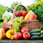 Wicker basket with assorted raw organic vegetables in the garden