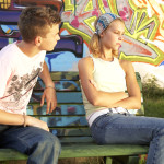 Young couple sitting at opposite ends of a bench.